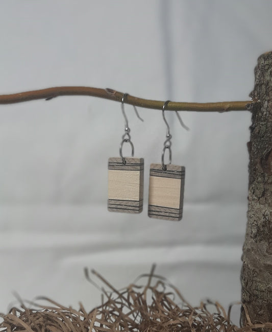 Wooden rectangular earrings hanging from a branch with a natural background