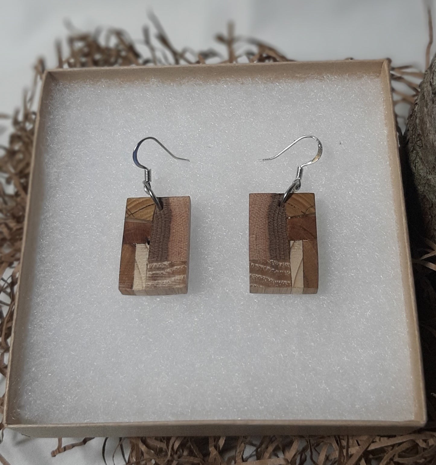 Wooden earrings on a textured white surface with natural wood background